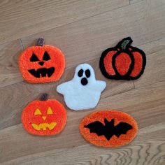 four pumpkins and two ghost patches on a wood floor