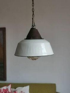 a white light hanging from a ceiling in a living room next to a green couch