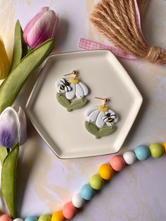 two earrings on a plate next to tulips