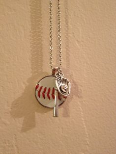 a baseball and bat necklace hanging from a chain