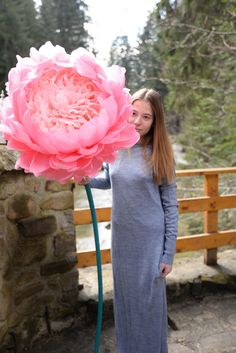 a woman holding a large pink flower in her hand