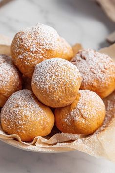 a bowl filled with powdered sugar covered pastries