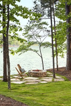 there is a fire pit in the middle of the grass near some trees and water