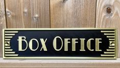 a metal box office sign mounted on a wooden fence with wood slats behind it