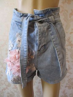 "Stone washed light denim shorts with pink embroidery and pink appliqued flowers on the front.  They have a high waist with a tie belt,  turned up hem, a zip fly and 2 pockets front and back. Waist flat;  30\" Outside leg from waist;  25\" Width of leg;  12\" Made by REAULAR cotton denim" Bohemian Style Denim Blue Jeans For Summer, Bohemian Denim Blue Jeans For Summer, Bohemian Cotton Jeans For Summer, Bohemian Style Cotton Summer Jeans, Summer Bohemian Denim Blue Jeans, Bohemian Summer Cotton Jeans, Bohemian Denim Blue Bottoms For Summer, Bohemian Style Light Wash Bottoms For Spring, Bohemian Light Wash Bottoms For Spring