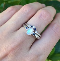 "A unique oval-shaped faceted rainbow moonstone engagement ring set accented with 2 petite genuine blue sapphires complemented with a matching contour wedding band featuring genuine blue and white sapphires handcrafted in sterling silver. Wrapped in a box ready for gift-giving.(r-egt-9) Instagram Video --------------- https://instagram.com/p/Bl3qWYXFgUA/ Can be custom made in any material and gemstones Center stone measure 7mm x 6mm Side Stone measures 2.2mm ----> Please note there is an addi Rainbow Moonstone Engagement Ring, Moonstone Engagement Ring Set, Sapphire Engagement Ring Set, Contour Wedding Band, Moonstone Engagement, Moonstone Engagement Ring, Sapphire Engagement Ring, Bridal Ring Set, Sapphire Engagement