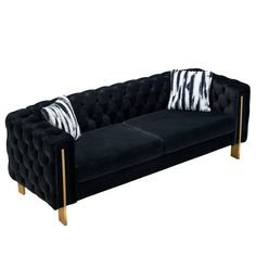 a black velvet couch with two zebra pillows on it's back and gold legs