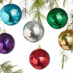 christmas ornaments hanging from a tree with pine needles in front of a white sky background