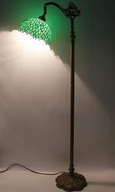 a floor lamp with a green shade on it's side and a white background