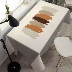 a white table with brown and tan paint on it in front of a window next to a chair