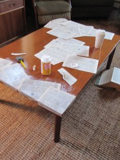 a coffee table covered in papers and glue sitting on top of a carpeted floor