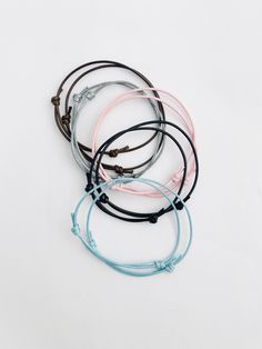 four bracelets with different colors and designs on them, one is black, the other is blue