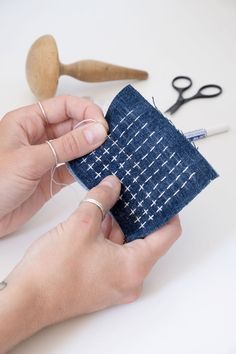 two hands are stitching fabric together with scissors