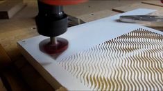 a machine that is cutting something out of some paper on a piece of plywood