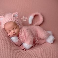 a newborn baby wearing a pink knitted bunny hat and sleeping on a pink blanket