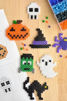 halloween themed perler beads are arranged on a wooden table next to a pencil and markers