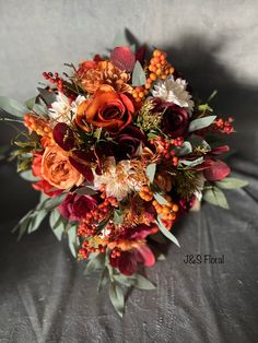 a bridal bouquet with orange, red and white flowers on a gray background in the sunlight