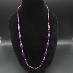 This purple Trifari necklace features a 30" L strand of purple beads with petite gold tone accent beads. It is signed Trifari on the clasp Purple Beaded Necklaces With Large Round Beads, Purple Oval Beaded Necklaces For Jewelry Making, Purple Single Strand Beads For Gift, Purple Necklaces With Colorful Round Beads, Single Strand Purple Beads For Gift, Purple Single Strand Beads As A Gift, Purple Beaded Vintage Necklace, Purple Beaded Oval Jewelry, Vintage Purple Beaded Necklace