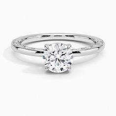 a white gold engagement ring with diamonds on the band and a round cut diamond in the center