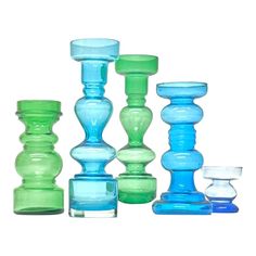 several different colored glass candlesticks on a white background