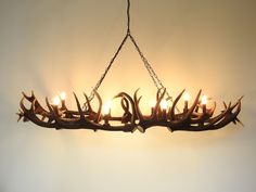 a chandelier made out of antlers with candles in them hanging from the ceiling