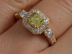 a close up of a person's hand with a yellow and white diamond ring