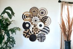 a wall hanging made out of woven circles and geometric designs with plants in the corner