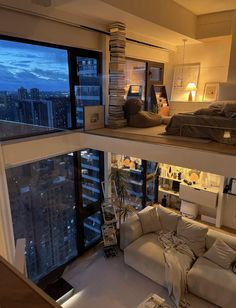 a living room filled with furniture and a large window overlooking the city at night time