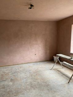 an empty room with a table and chair in it, next to a large window