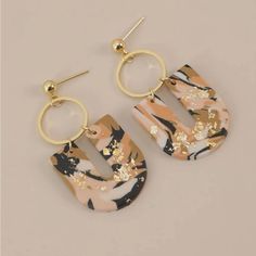 two pairs of earrings with gold and black designs on them, one is shaped like an oval