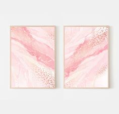 two pink and gold paintings hanging on a wall