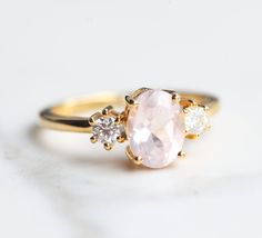 With a brilliant cut like that, this ring is nothing but pure brilliance in itself. With the prettiest pastel color of the Rose Quartz, the Khloe ring with two side moissanite sparkles like there is no tomorrow. Celebrate your milestones or special occasions with this ring as the perfect gift for a new mom, as a best friend's gift, or just as an everyday celebration of life in general. Details: Center stone Gemstone: Rose Quartz Stone Shape: Oval Measurements: approx. 9x7mm Side stones Gemstone: Oval Rose Cut Diamond Promise Ring, Oval Morganite Wedding Ring With Rose Cut Diamonds, Oval Morganite Wedding Ring With Brilliant Cut, Blush Diamond Ring With Center Stone, Oval Morganite Diamond Ring For Wedding, Oval Blush Rings For Wedding, Blush Oval Rings For Wedding, Blush Oval Wedding Rings, Delicate Oval Ring With Center Stone