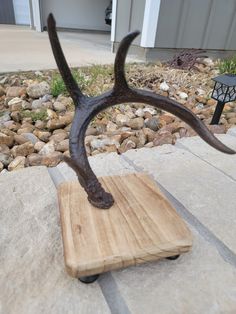 an antelope sculpture sitting on top of a wooden block in front of a house