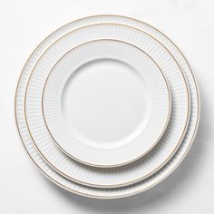 three white and gold plates stacked on top of each other, with one empty plate in the middle