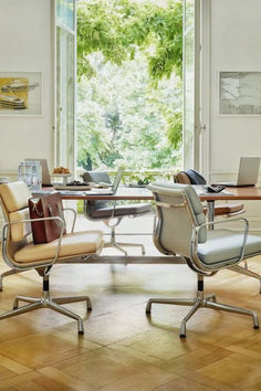 two office chairs sitting in front of a table with a laptop computer on top of it