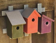 three colorful bird houses hanging on the side of a wooden door