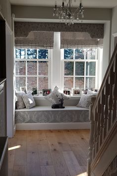 a window seat in the corner of a living room with pillows on it and a chandelier hanging from the ceiling