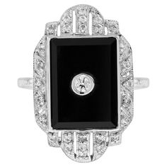 A stunning, fine and impressive Art Deco style diamond and onyx halo ring. A total of 0.058 carats of diamond are set in square shaped onyx. A stunning piece to match with your everyday look. Ring Information Style: Art-deco Metal: 14K White Gold Weight: 4.30 g. (approx. total weight) Center Gemstones Type: Diamond Shape: Round Average Color: H Average Clarity: SI Size: 2.3 mm. Number: 1 Weight: 0.058 Carat (approx. total weight) Accent Gemstones Type: Onyx Shape: Square Number: 1 Accent Gemston Formal White Gold Diamond Ring With Rectangular Stone, Formal Diamond Ring With Rectangular Center Stone, Elegant Black Enamel Diamond Ring For Anniversary, Elegant Square Cut Halo Ring, Elegant Black Enamel Rings For Evening, Elegant Ring With Rectangular Center Stone, Elegant Diamond Ring With Black Enamel, Elegant Diamond Ring With Black Enamel As Gift, Elegant Diamond Ring With Black Enamel For Gift