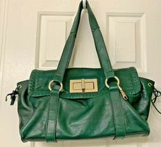 HYPE Green Leather Satchel Barrel shape Handbag Purse. Made of soft supple Leather .Slouch style with Double straps long enough to fit over shoulder. Flap front with attractive leather cord stitching . Bold GoldTone Turn Lock closure ( see pics) . Leather ties on both sides of bag . Gold tone key clip on front . Large deep outside compartment on back ; zippered. Fully lined with a Tan color Paisley fabric. Roomy with four inside compartments three open and one large zippered one. A really nice s