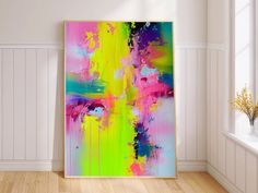 an abstract painting is displayed in the corner of a room with white walls and wooden floors