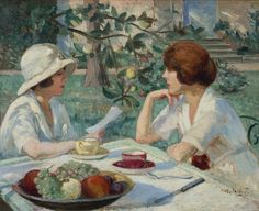 two women sitting at a table with fruit on the plate and one holding a paper