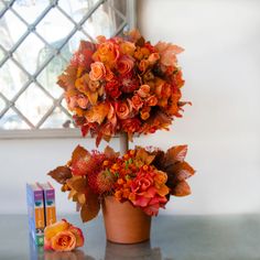 an arrangement of flowers in a pot on a table next to a box of tissues