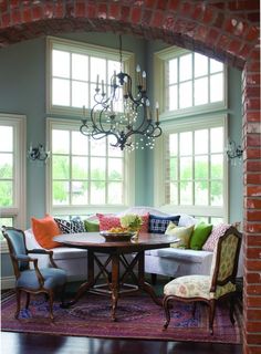 a living room filled with furniture and a chandelier hanging from a brick wall