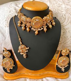 Browse our stunning Desi Asian Gold Choker set with beautifully matched Earrings & Tikka! Our gold choker set features intricate designs inspired by the diverse cultures of Pakistan / India - Each piece is crafted with high-quality materials, included lustrous gold and cream embellishments that add a touch of sophistication.  The gold, bridal choker sits gracefully on the neck, enhancing your neckline and adding a touch of allure to your look - Complete the ensemble with the matching desi earrings and tikka, which beautifully harmonise with the ethnic choker. Shop now and immerse yourself in the beauty and ethnic elegance of these treasures that bridge tradition and modernity. Perfect for weddings/Nikkah, Eid, Diwali and many more special occasions or cultural events. Please note that due Desi Earrings, Gold Choker Set, Pakistan Culture, Indian Choker, Wedding Unique, Bridal Choker, Choker Style Necklace, Indian Jewelry Sets, Choker Set