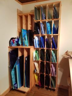 a wooden shelf filled with lots of different colored folders and papers on top of it