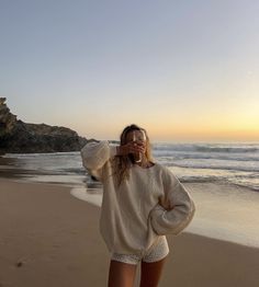 a woman standing on top of a beach next to the ocean