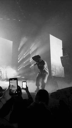 a man standing on top of a stage holding a cell phone in front of him