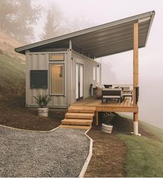 a house made out of shipping containers on top of a hill with stairs leading up to it