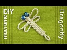 a white and blue dragonfly brooch on a green cloth with two small blue flowers