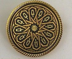 an ornate gold and black broochle on a white background